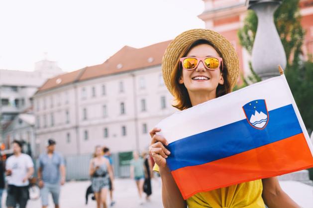 Žena drží slovinskou vlajku.