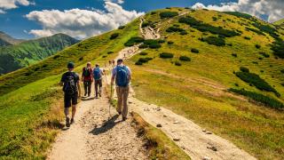 Skupina turistů stoupající po značené stezce.