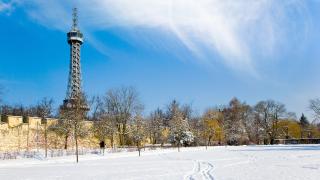 Zasněžený park s Petřínskou rozhlednou v pozadí.