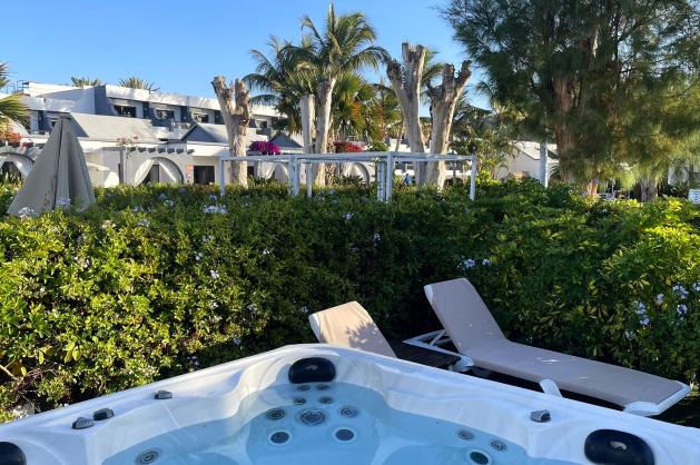 Soukromá vířivka obklopená zelení a lehátky 