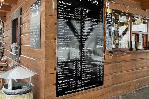 Horský stánek s jídlem obklopený sněhem a zimní výzdobou.