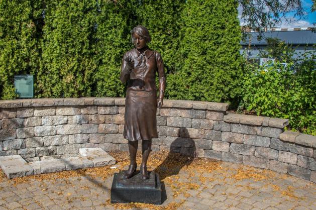 Bronzová socha ženy s ciferníkem v ruce