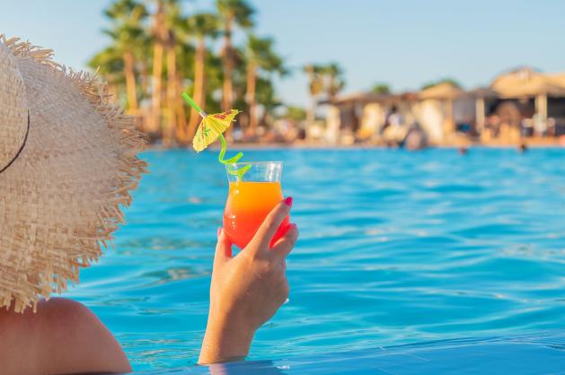 Žena s kloboukem drží drink 