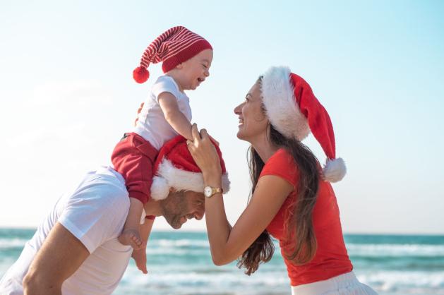 Rodiče a malé dítě v červených vánočních čepicích 