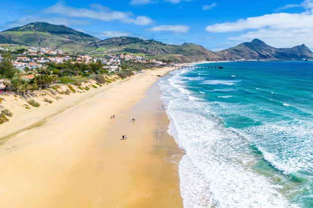 Dlouhá písečná pláž na ostrově Porto Santo obklopená horami.