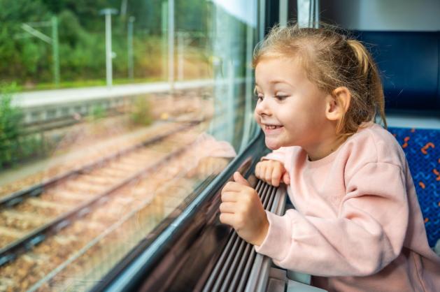 Malá holčička kouká z okna vlaku