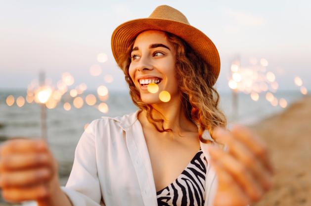 Mladá žena s prskavkami na pláži.