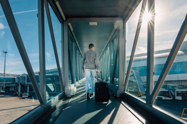 Cestující prochází tunelem k letadlu.