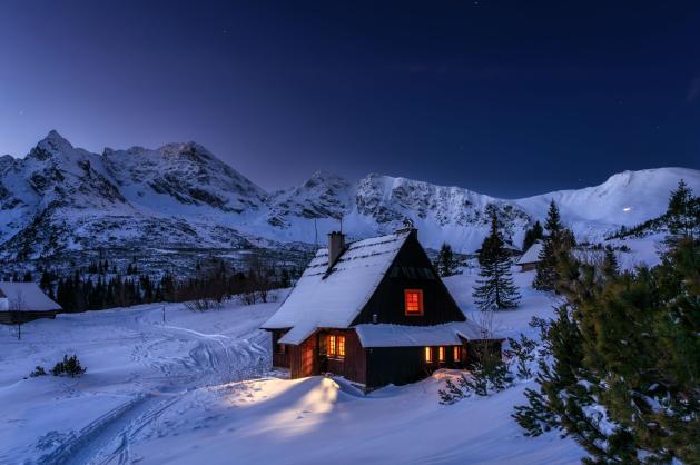 Dřevěná chata zasypaná sněhem v horách