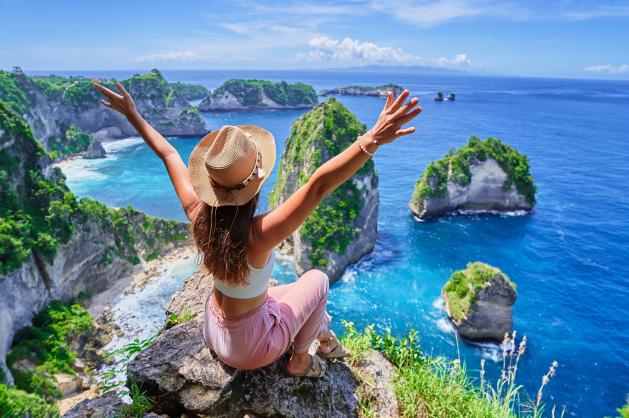 Žena sedící na skalním útesu s rozpaženýma rukama 