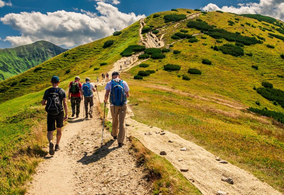 Skupina turistů stoupající po značené stezce.