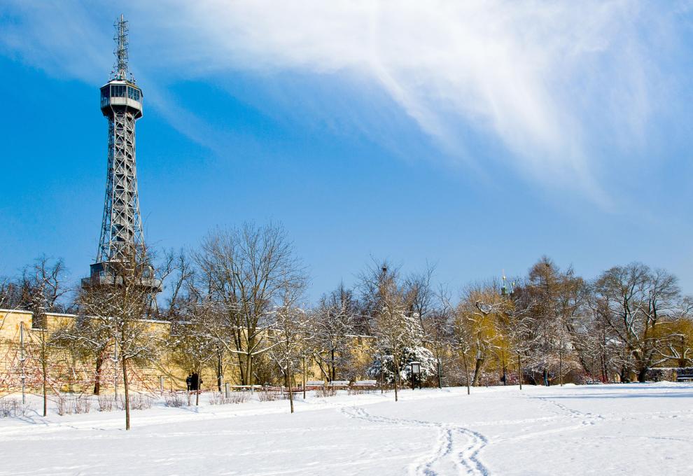 Zasněžený park s Petřínskou rozhlednou v pozadí.