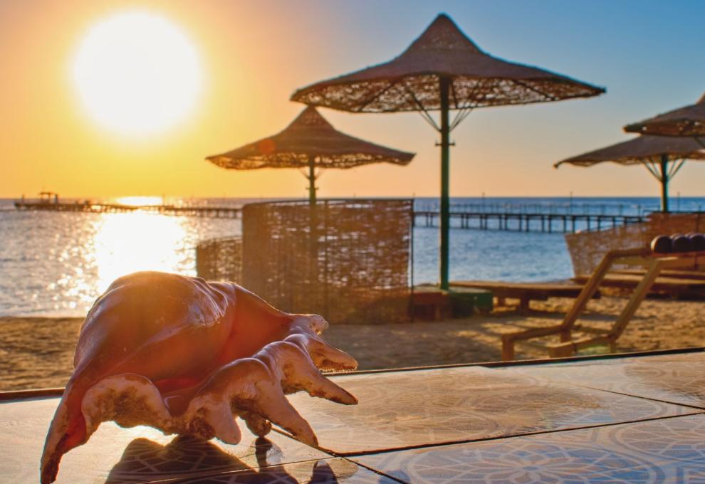 Pláž při západu slunce s lehátky a slunečníky