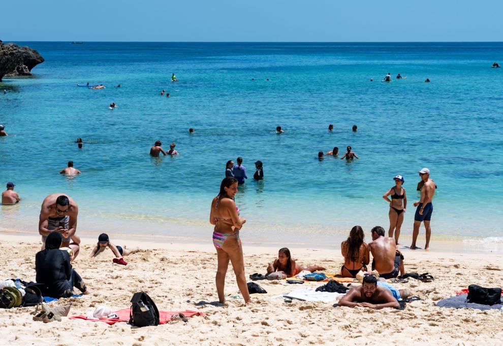 Rušná písečná pláž s koupajícími se lidmi 