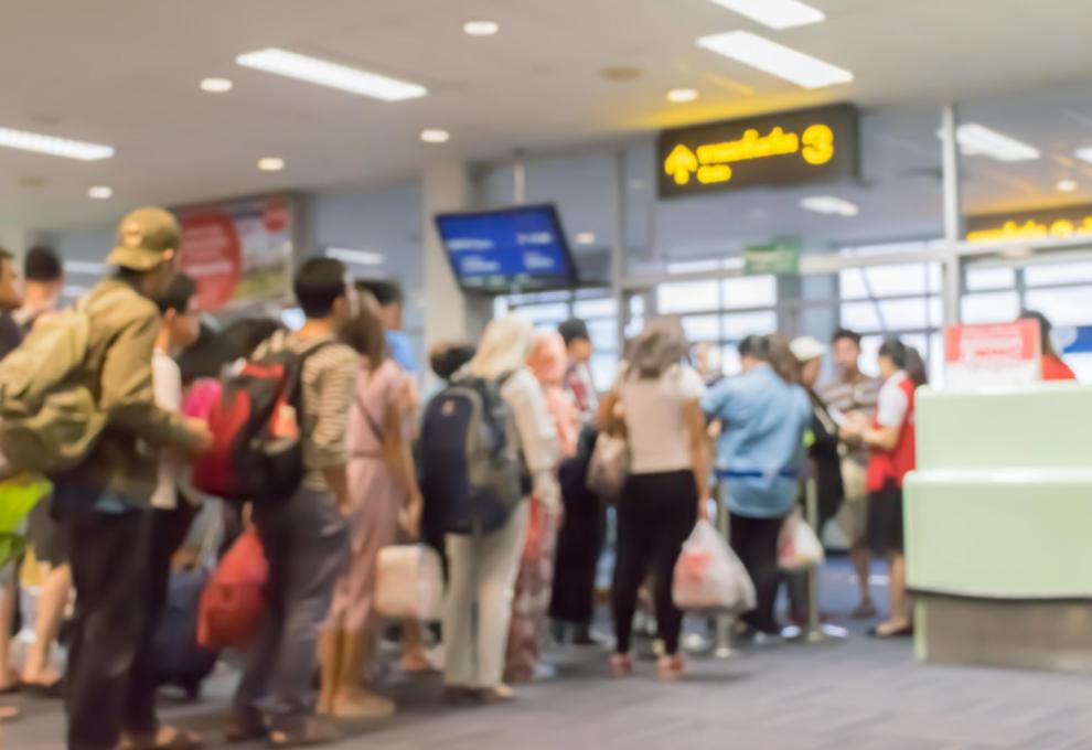 Skupina lidí čeká v řadě během odbavovacího procesu