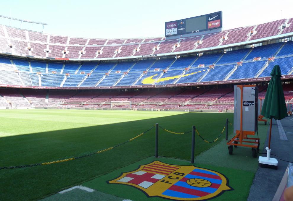 Logo týmu FC Barcelona v trávníku u laviček na fotbalovém stadionu Camp Nou. - Cestovinky.cz