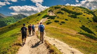 Skupina turistů stoupající po značené stezce.