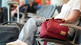 Cestující sedí v hale s příručním zavazadlem 