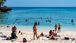 Rušná písečná pláž s koupajícími se lidmi 