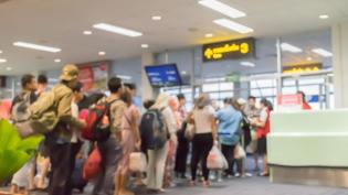 Skupina lidí čeká v řadě během odbavovacího procesu