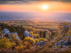 Podzimní krajina s vinicemi, lesy a skalisky při západu slunce