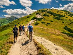 Skupina turistů stoupající po značené stezce.