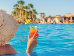 Žena s kloboukem drží drink 