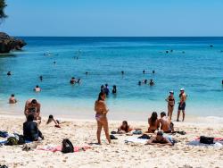 Rušná písečná pláž s koupajícími se lidmi 