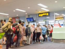 Skupina lidí čeká v řadě během odbavovacího procesu